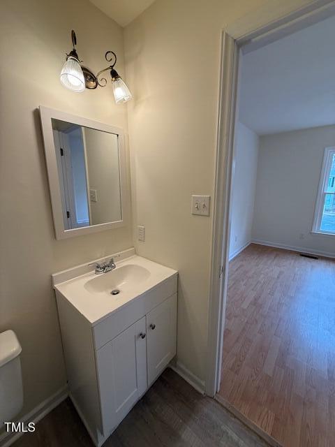 bathroom featuring toilet, vanity, baseboards, and wood finished floors