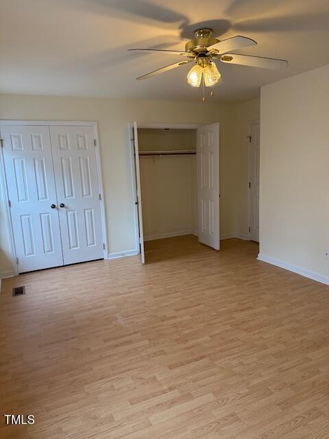 unfurnished bedroom featuring visible vents, light wood-style floors, multiple closets, and baseboards