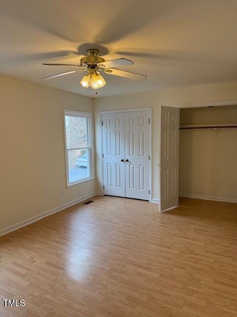 unfurnished bedroom with light wood finished floors, baseboards, visible vents, and two closets