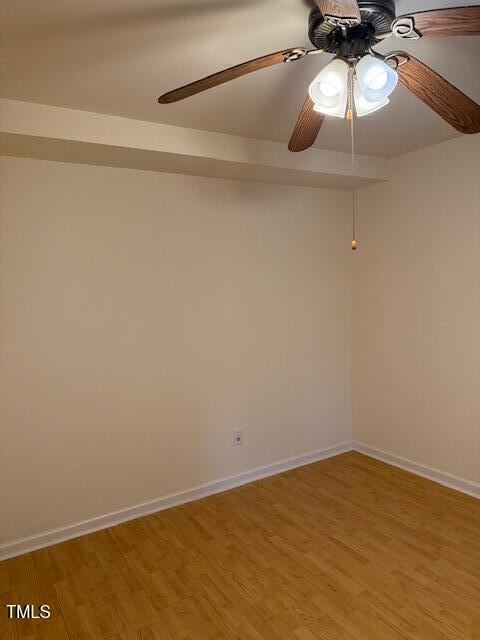 spare room with a ceiling fan, light wood-style floors, and baseboards