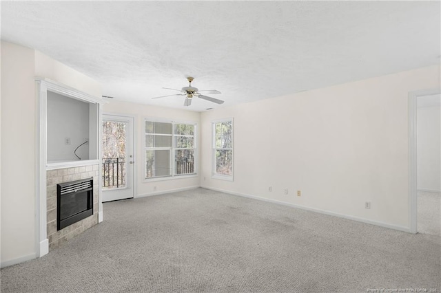 unfurnished living room featuring a textured ceiling, carpet floors, a ceiling fan, baseboards, and a tiled fireplace