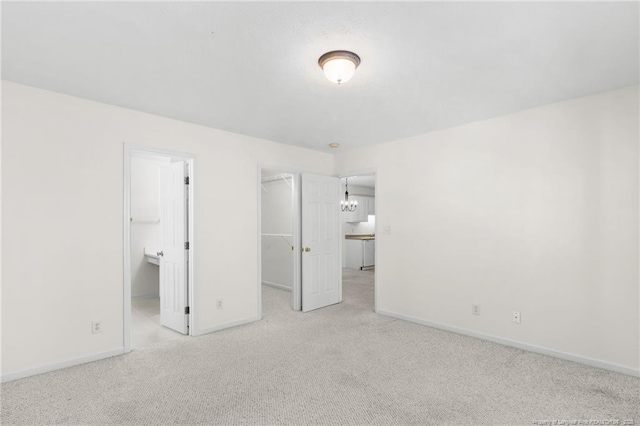 unfurnished bedroom with carpet floors, a walk in closet, a closet, and baseboards