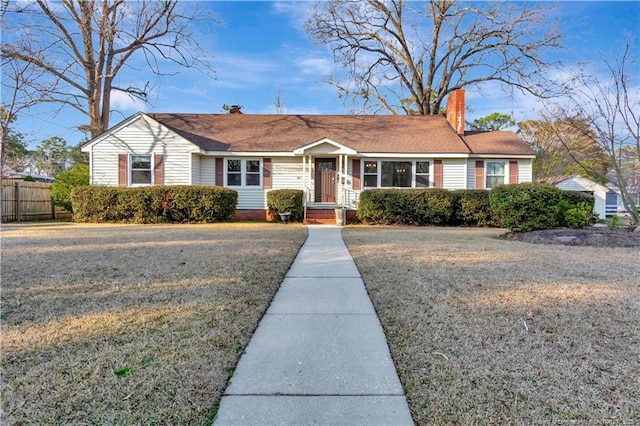 ranch-style home with a front yard, fence, and a chimney