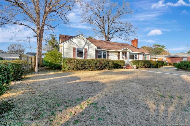 ranch-style house with a chimney and fence