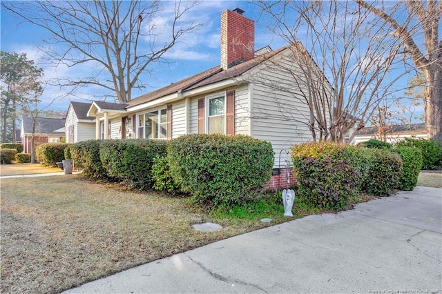 view of side of home with a yard and a chimney