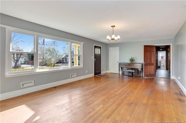 entrance foyer with an inviting chandelier, light wood-style flooring, and baseboards