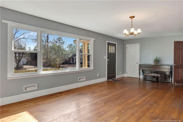 foyer with an inviting chandelier, baseboards, and wood finished floors