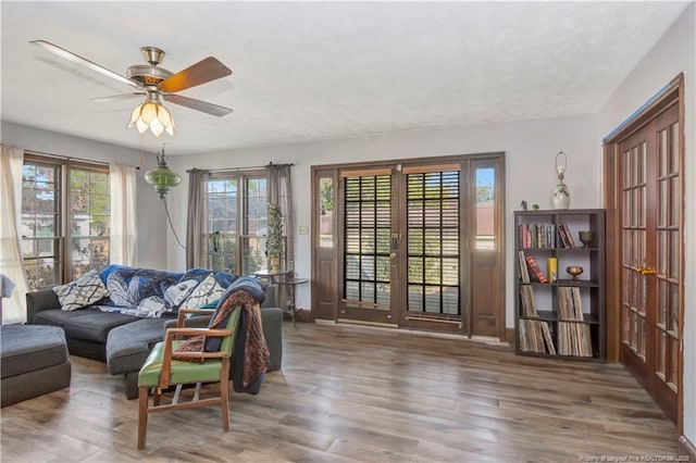 living room with a ceiling fan, french doors, baseboards, and wood finished floors