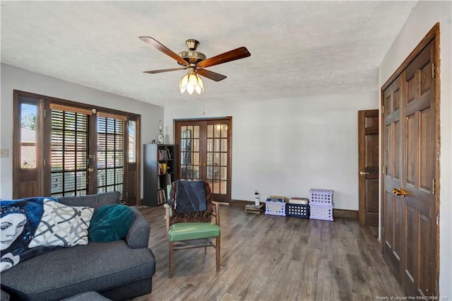 living area with french doors, a ceiling fan, a textured ceiling, wood finished floors, and baseboards