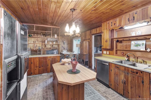 kitchen with wood walls, a sink, wood ceiling, stainless steel dishwasher, and brown cabinetry