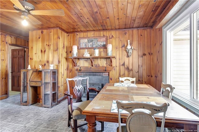 dining area featuring ceiling fan, wood walls, and wooden ceiling