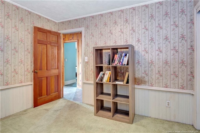 interior space with crown molding, wainscoting, and wallpapered walls