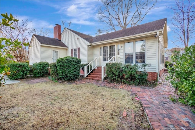 view of front of home featuring entry steps, a front lawn, and a chimney