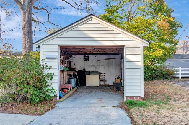 view of outbuilding with driveway, fence, and an outdoor structure