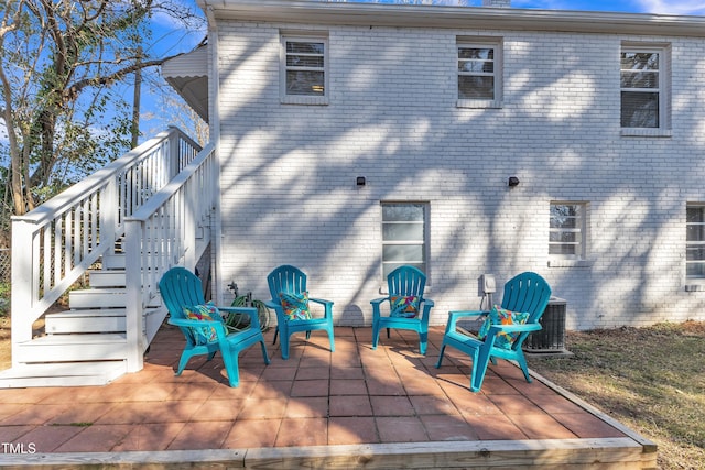 back of house featuring stairs, brick siding, and a patio area