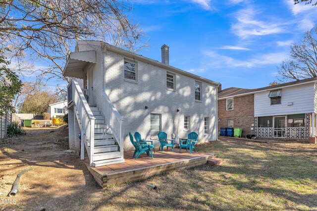 rear view of house featuring a sunroom, a chimney, stairs, a yard, and brick siding