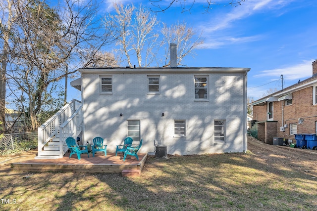 back of house featuring a yard, a chimney, central AC, and brick siding