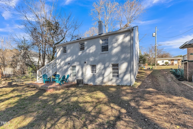 rear view of property featuring a lawn, a chimney, stairs, fence, and brick siding