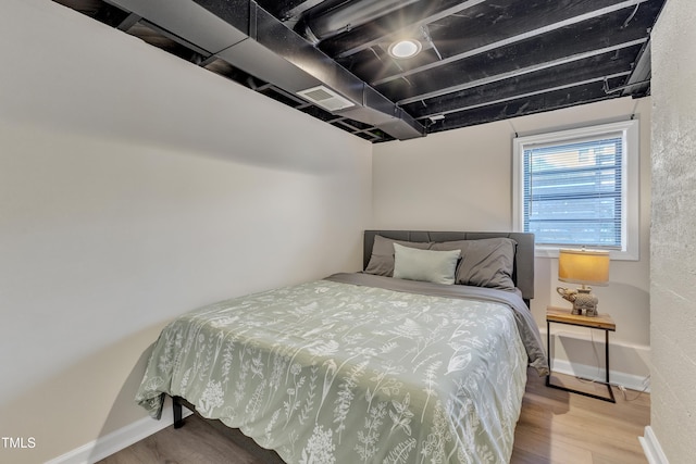 bedroom featuring visible vents, baseboards, and wood finished floors