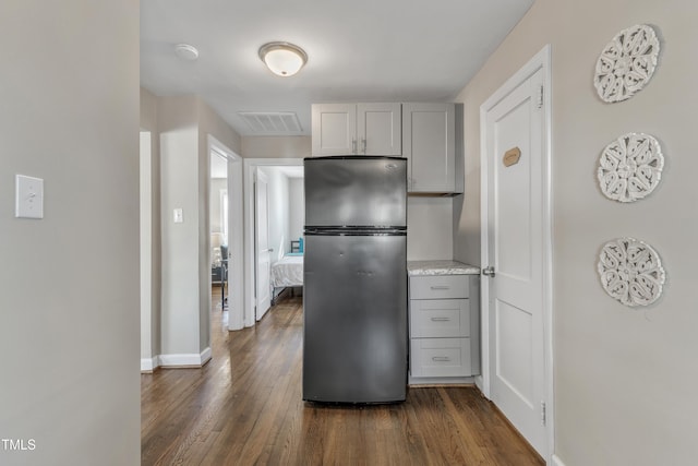 kitchen featuring gray cabinetry, visible vents, dark wood-style flooring, and freestanding refrigerator