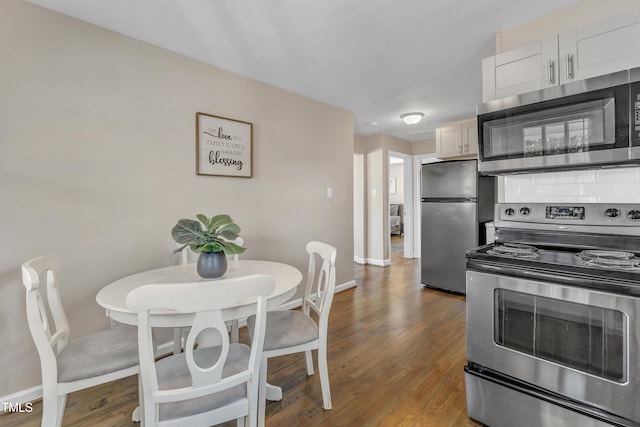 kitchen featuring stainless steel appliances, tasteful backsplash, wood finished floors, and baseboards