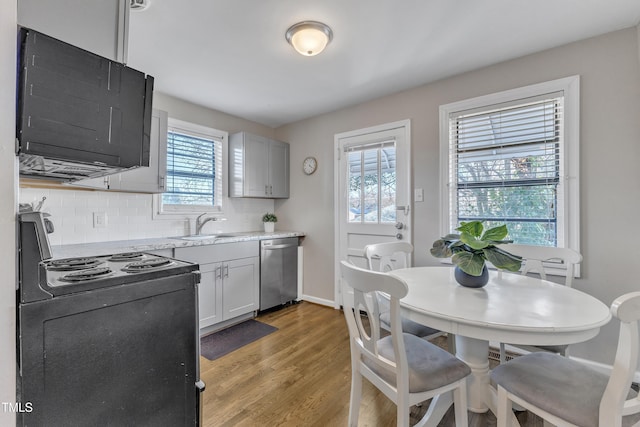 kitchen with tasteful backsplash, dishwasher, black electric range oven, light wood-style floors, and a sink