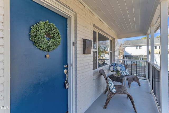 exterior space with a porch and brick siding