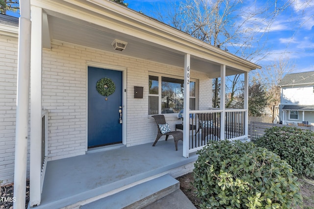 entrance to property with covered porch and brick siding