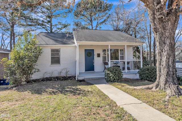 view of front of house featuring a porch, a front yard, and brick siding