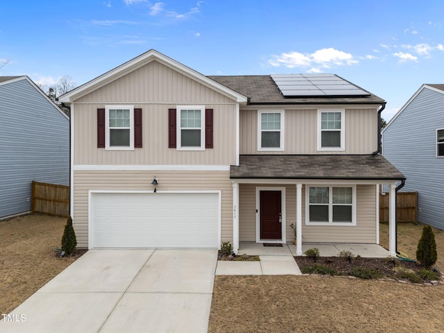 traditional home with concrete driveway, fence, a garage, and roof mounted solar panels