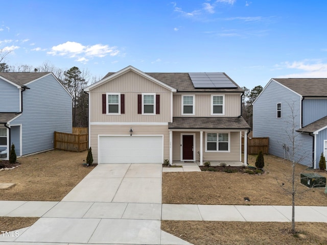 traditional-style home featuring solar panels, concrete driveway, fence, and a garage