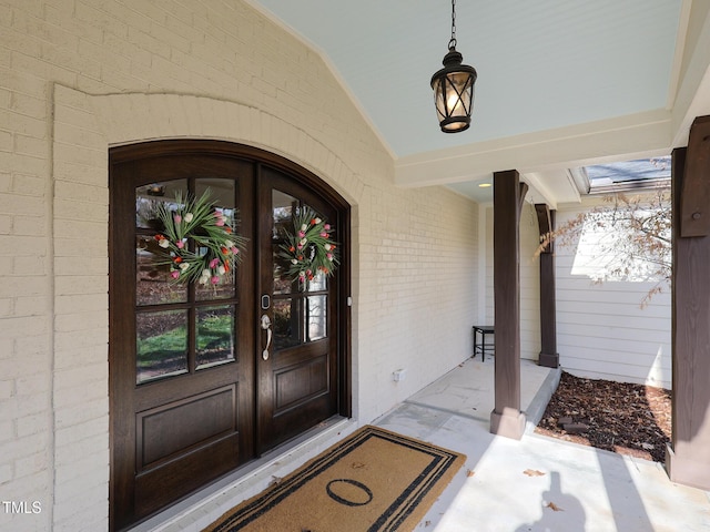 view of exterior entry featuring covered porch and brick siding