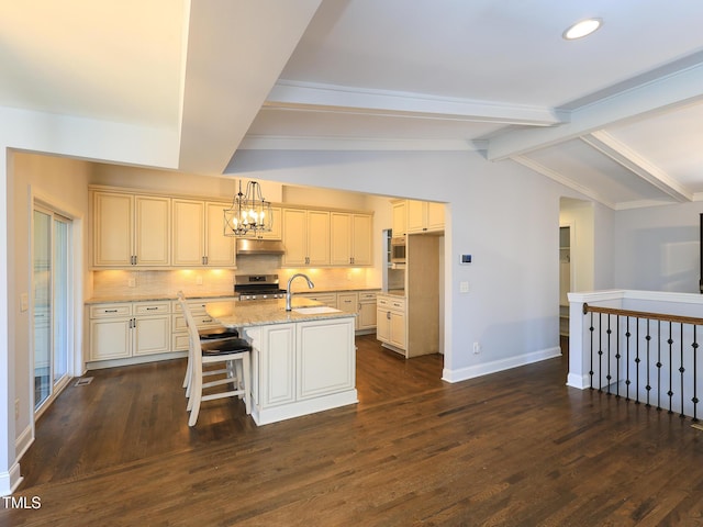 kitchen featuring vaulted ceiling with beams, light stone countertops, under cabinet range hood, decorative backsplash, and stainless steel stove