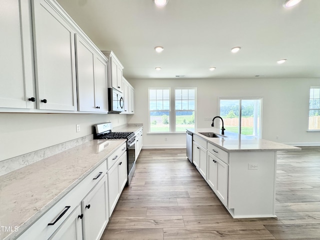 kitchen featuring recessed lighting, a sink, white cabinetry, appliances with stainless steel finishes, and light wood finished floors