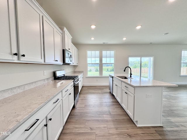 kitchen featuring light wood finished floors, appliances with stainless steel finishes, white cabinetry, a sink, and recessed lighting