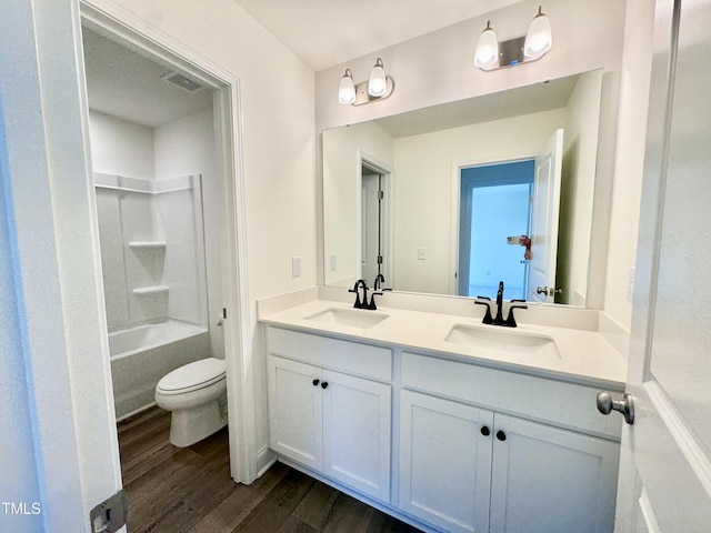 bathroom featuring double vanity, visible vents, a sink, and wood finished floors