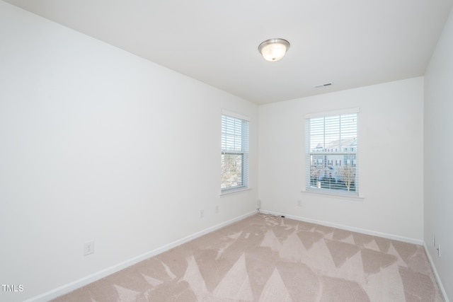 spare room with light carpet, visible vents, and baseboards