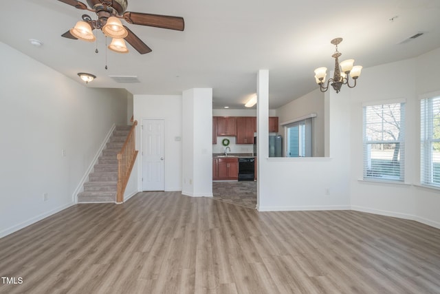 unfurnished living room featuring a sink, light wood-style flooring, baseboards, and stairs