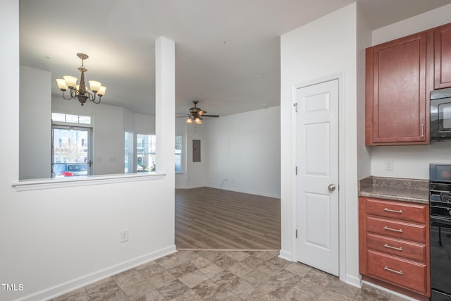 interior space featuring baseboards, black microwave, open floor plan, and ceiling fan with notable chandelier