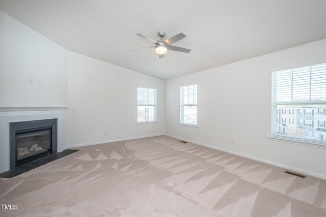 unfurnished living room featuring visible vents, a fireplace with flush hearth, light carpet, vaulted ceiling, and baseboards