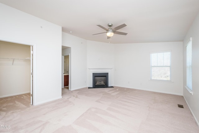 unfurnished living room with a fireplace with flush hearth, visible vents, baseboards, and light colored carpet