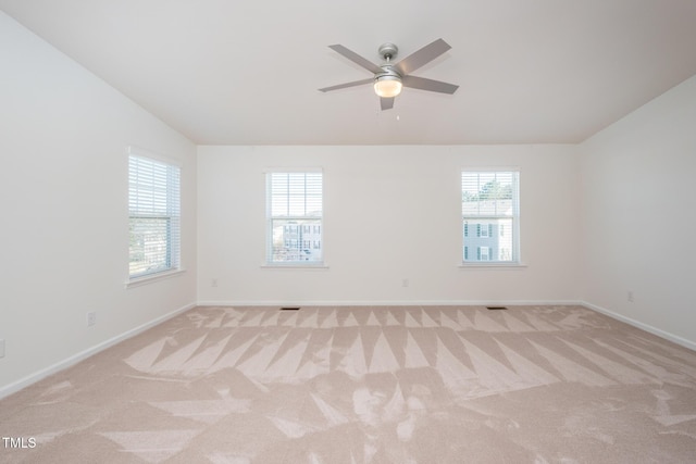 empty room featuring light carpet, baseboards, vaulted ceiling, and a ceiling fan