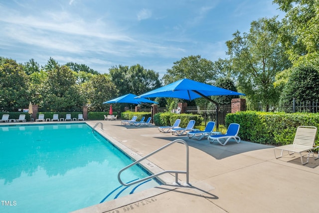 pool with a patio area and fence