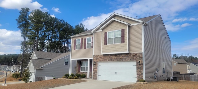 view of front of house with concrete driveway, fence, a garage, cooling unit, and stone siding