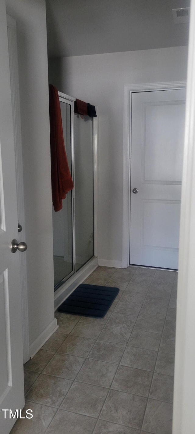 bathroom featuring a shower stall and baseboards