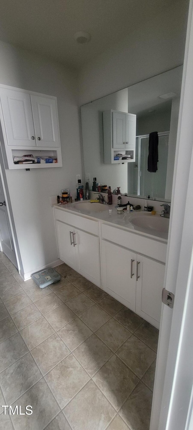 full bathroom featuring tile patterned flooring, a sink, a shower stall, and double vanity