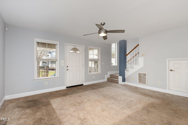 carpeted foyer entrance featuring visible vents, ceiling fan, stairway, and baseboards