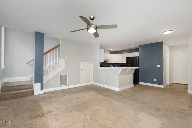 unfurnished living room featuring visible vents, light colored carpet, stairway, and baseboards