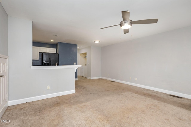 unfurnished living room featuring visible vents, baseboards, light colored carpet, and ceiling fan