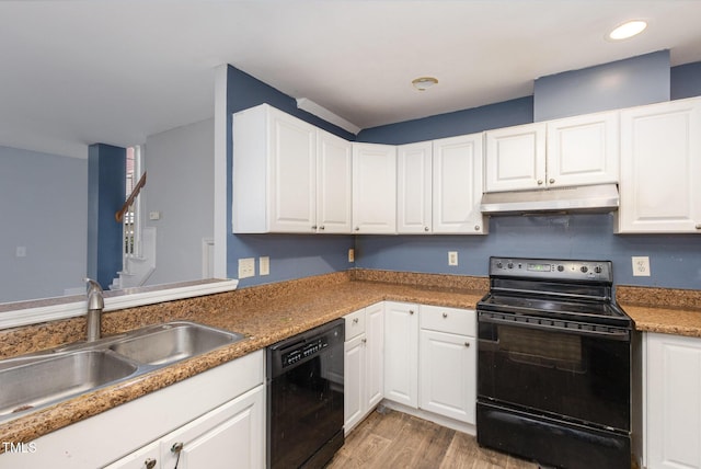 kitchen featuring under cabinet range hood, light wood-type flooring, white cabinets, black appliances, and a sink